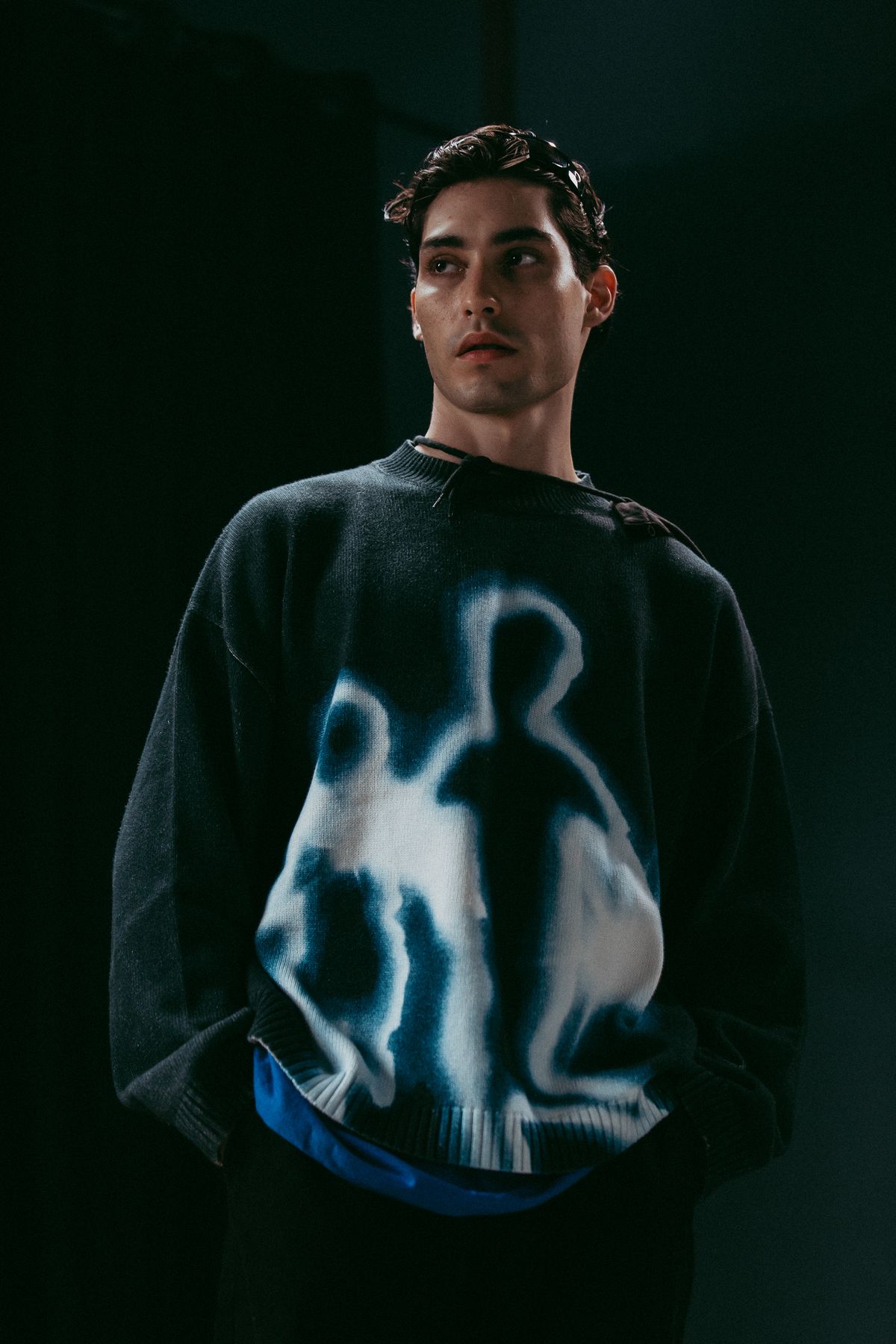 Model in a dark sweater with a glowing figure print