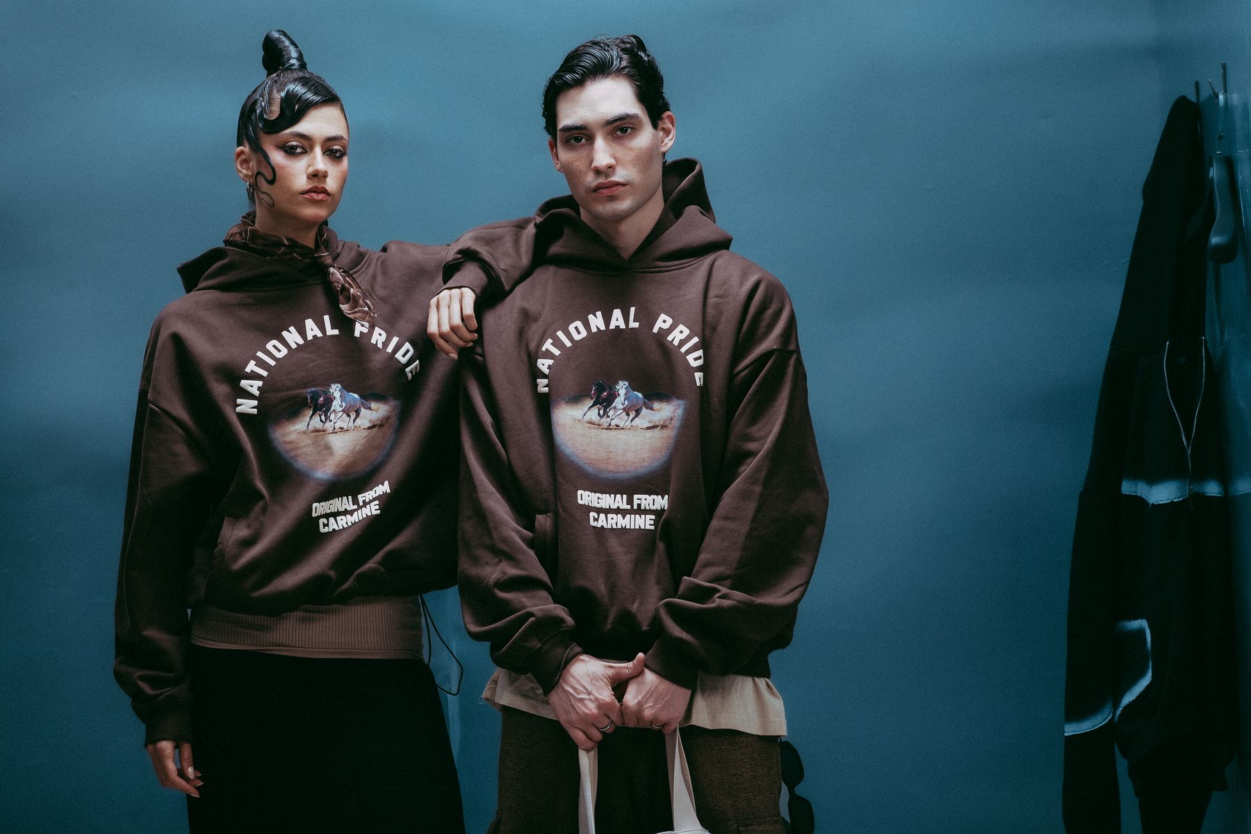 Two models in brown hoodies in the blue room