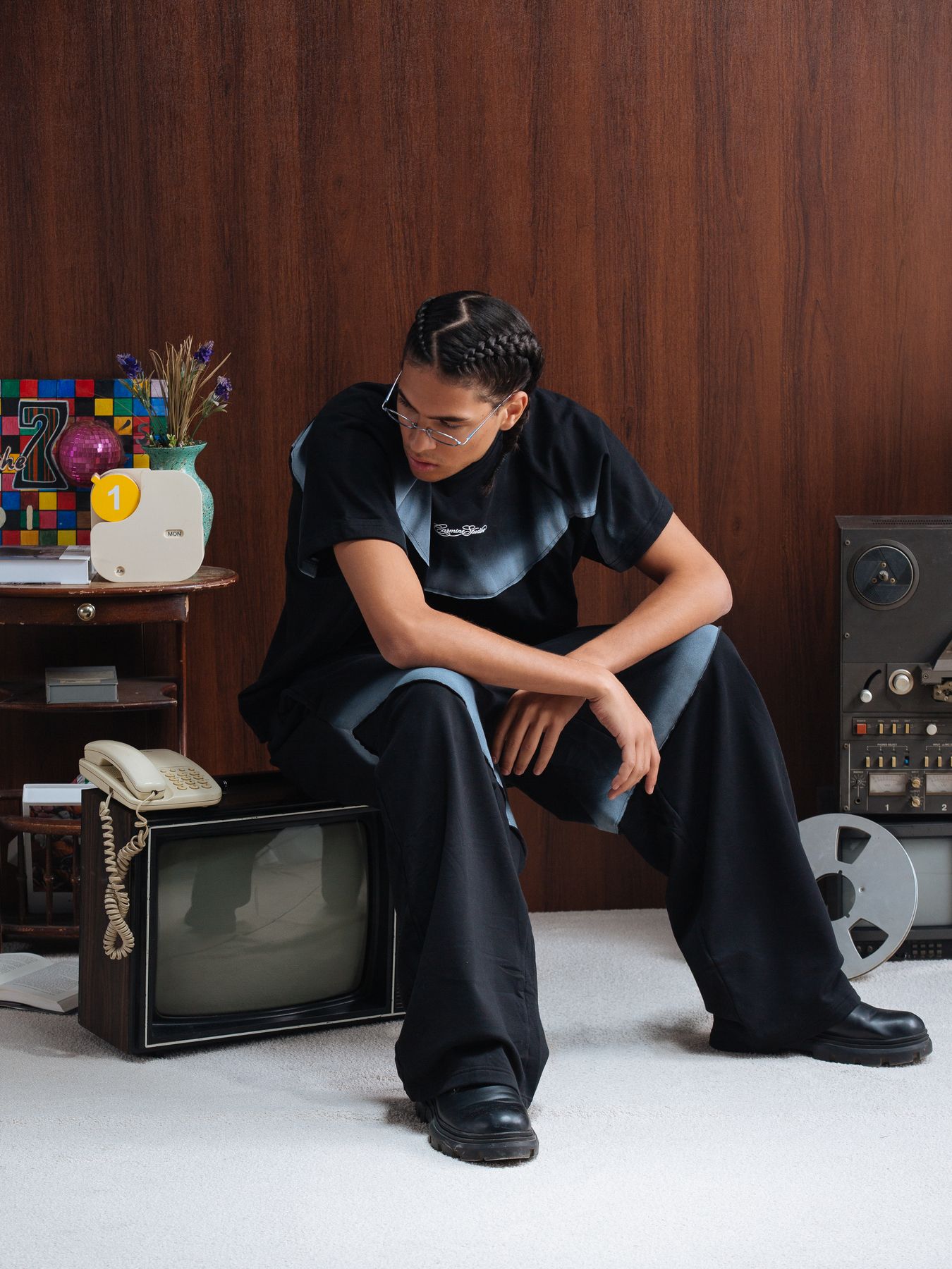 Model seated with a television and plant